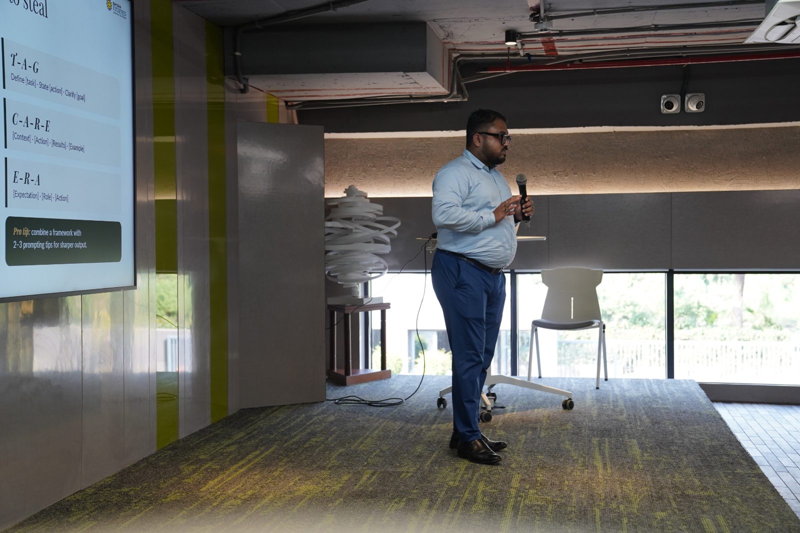 Sourish Mukherjee presenting beside the prompt-frameworks slide, microphone in hand.